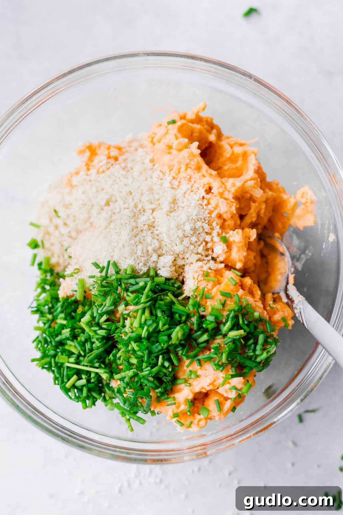 Ingredients for Leftover Cheesy Potato Pancakes A bowl filled with the raw mixture for cheesy potato pancakes, featuring mashed potatoes, shredded cheese, and green onions, ready for cooking.