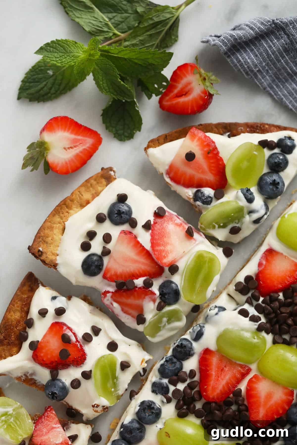 Effortless Fruit Pizza 2 Finished fruit pizza on a cutting board, garnished with an array of fresh, vibrant fruits.