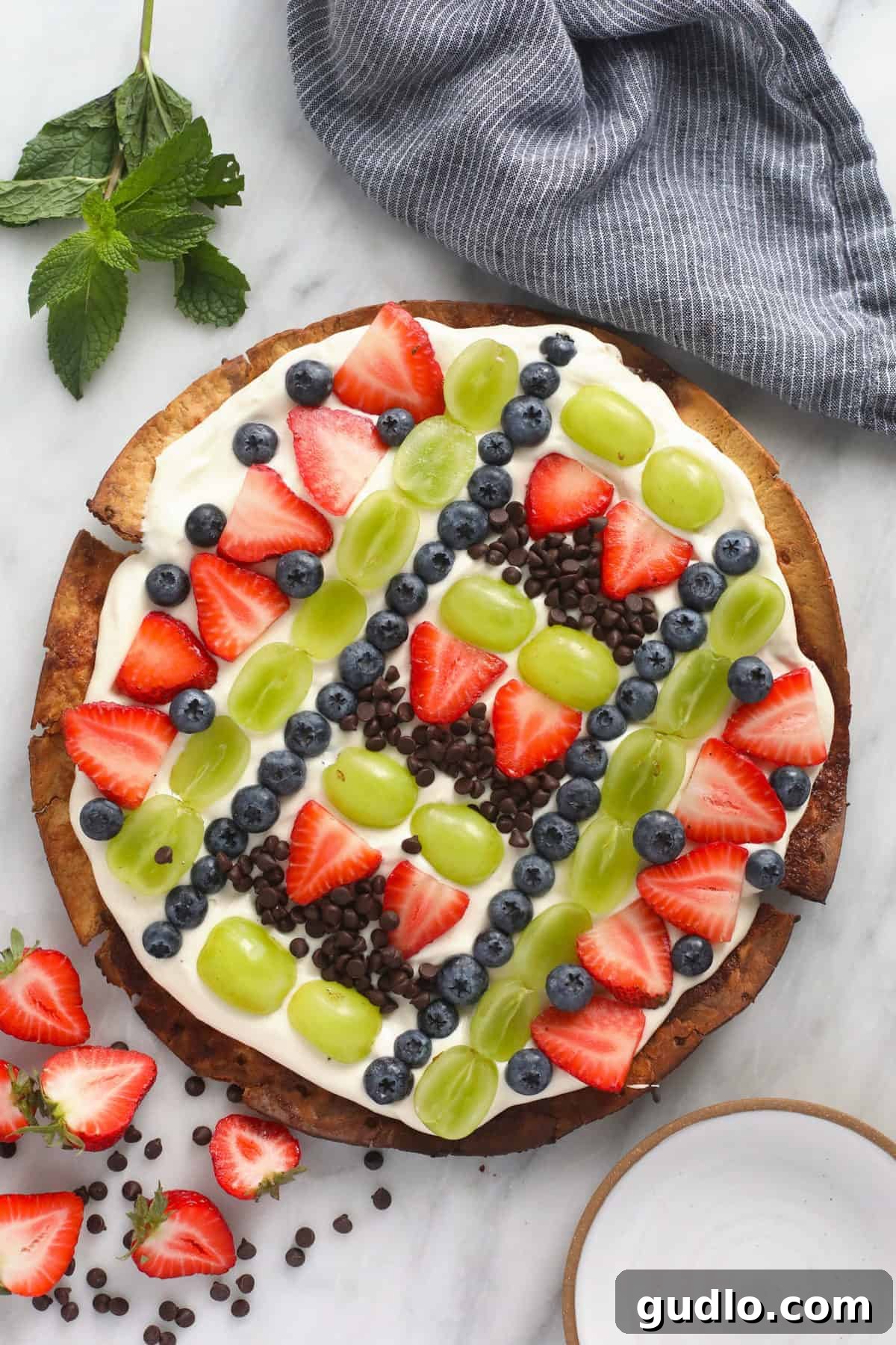 Effortless Fruit Pizza 5 A vibrant fruit pizza, topped with an assortment of fresh berries and chocolate chips, ready to be served on a kitchen counter.