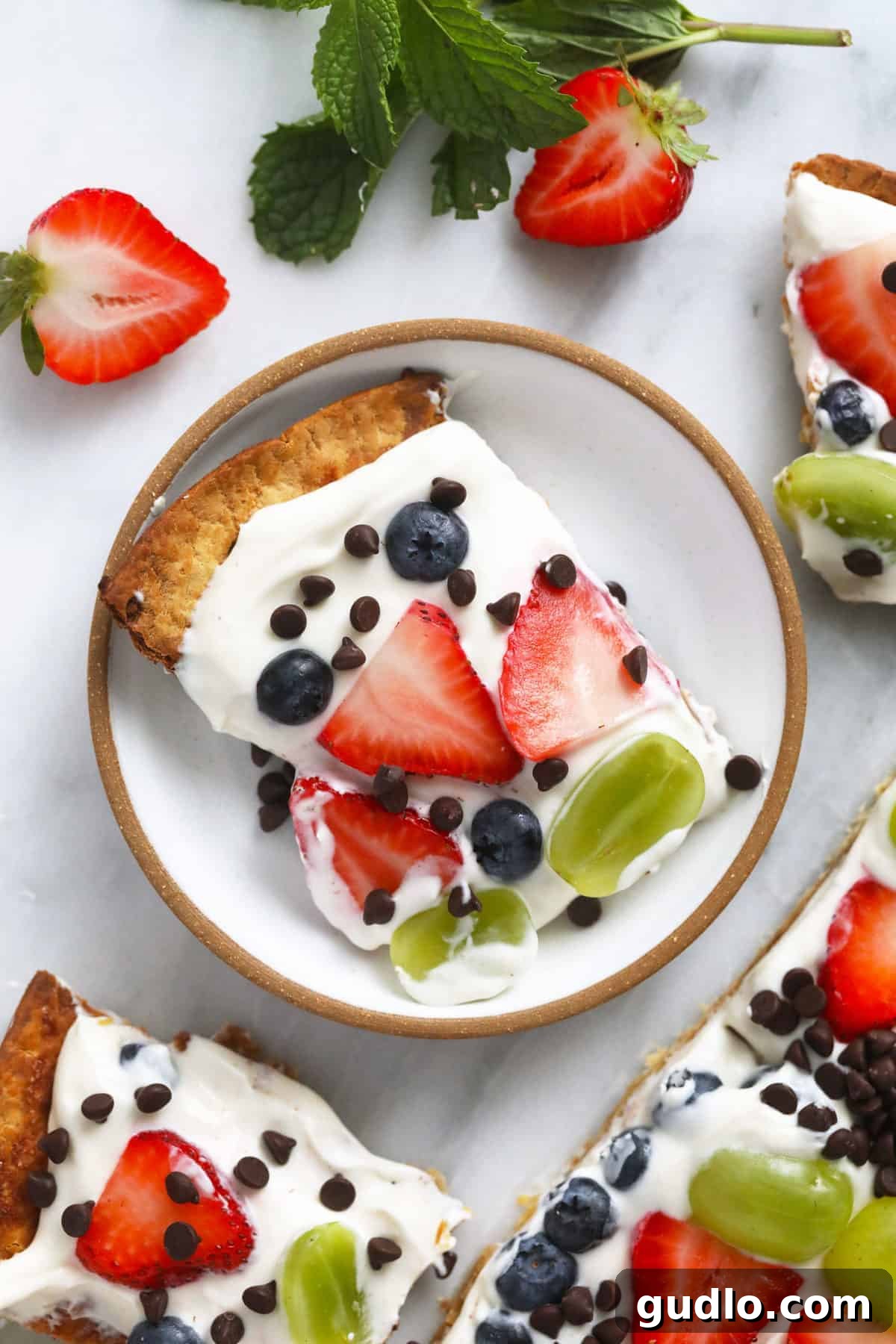 Effortless Fruit Pizza 6 A delightful slice of fruit pizza elegantly presented on a small white plate, ready to be enjoyed.