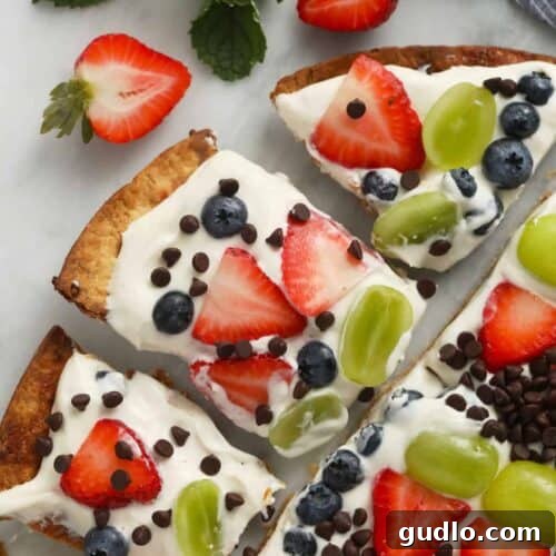 Easy fruit pizza on a cutting board, ready to be sliced.