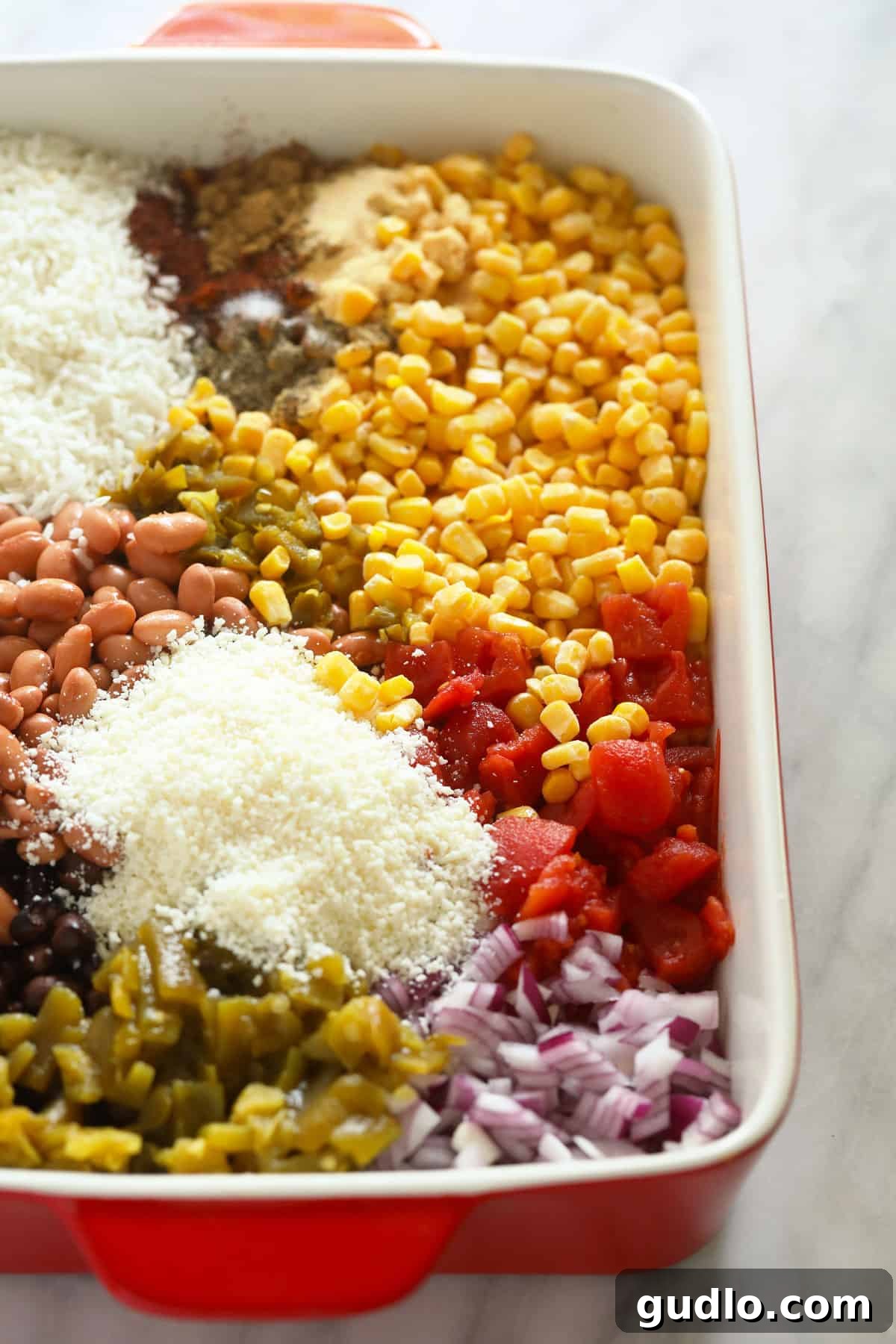 Prepping the Mexican Street Corn Casserole: Fresh ingredients awaiting their delicious transformation. All the vibrant ingredients for Mexican street corn casserole are neatly arranged within a 9x13-inch casserole dish, ready to be mixed and baked.