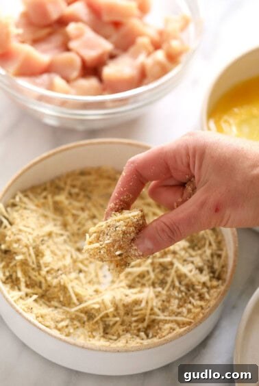 Dipping chicken into bread crumbs.
