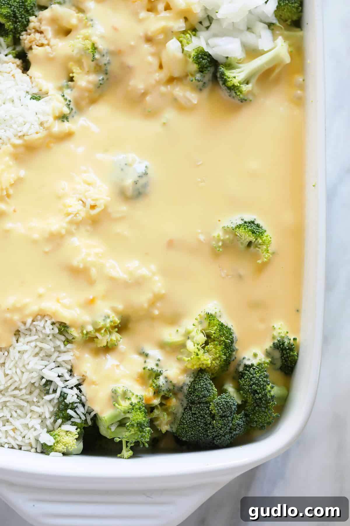 Close-up of broccoli and cheese ingredients in a casserole dish, perfectly blended before baking.