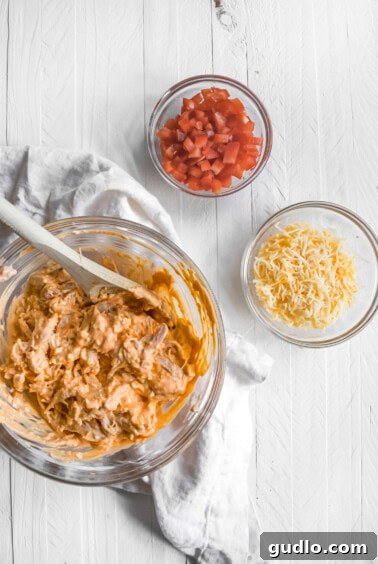 A large bowl containing all the creamy, spicy ingredients for a delicious Buffalo dip, expertly mixed and ready to coat shredded chicken for nachos.