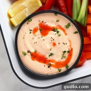 A bowl of lusciously smooth and creamy Buffalo Whipped Cottage Cheese Dip, elegantly garnished with fresh chives and a swirl of spicy buffalo sauce, ready for dipping.