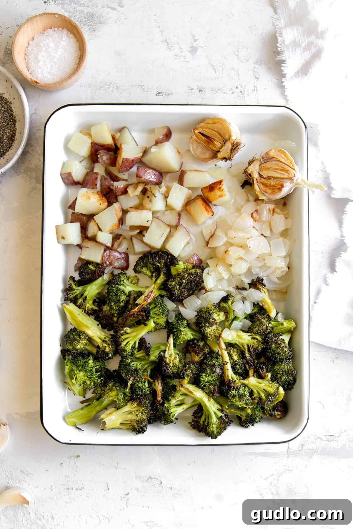 Velvety Broccoli & Cheddar 5 Perfectly roasted broccoli, onion, garlic, and potato cubes arranged on a baking sheet, golden and tender.