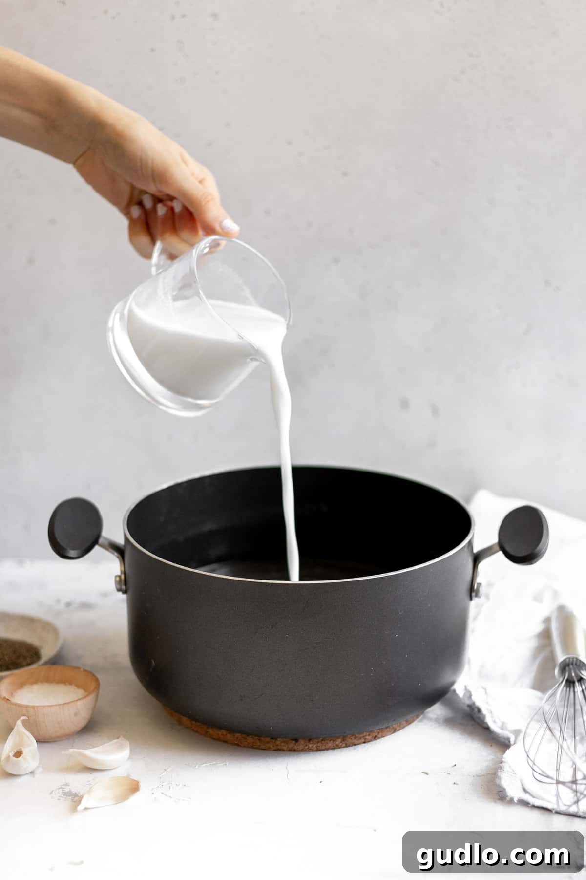 Velvety Broccoli & Cheddar 6 Pouring milk into a stockpot filled with savory chicken broth, creating the creamy base for the soup.