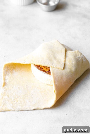 folding puff pastry over brie cheese.