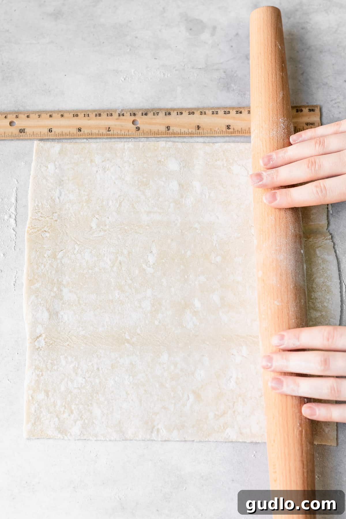 rolling out puff pastry on a floured surface.