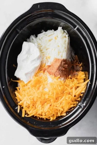 A cheesy crock pot filled with potatoes, stirred and ready for cooking.