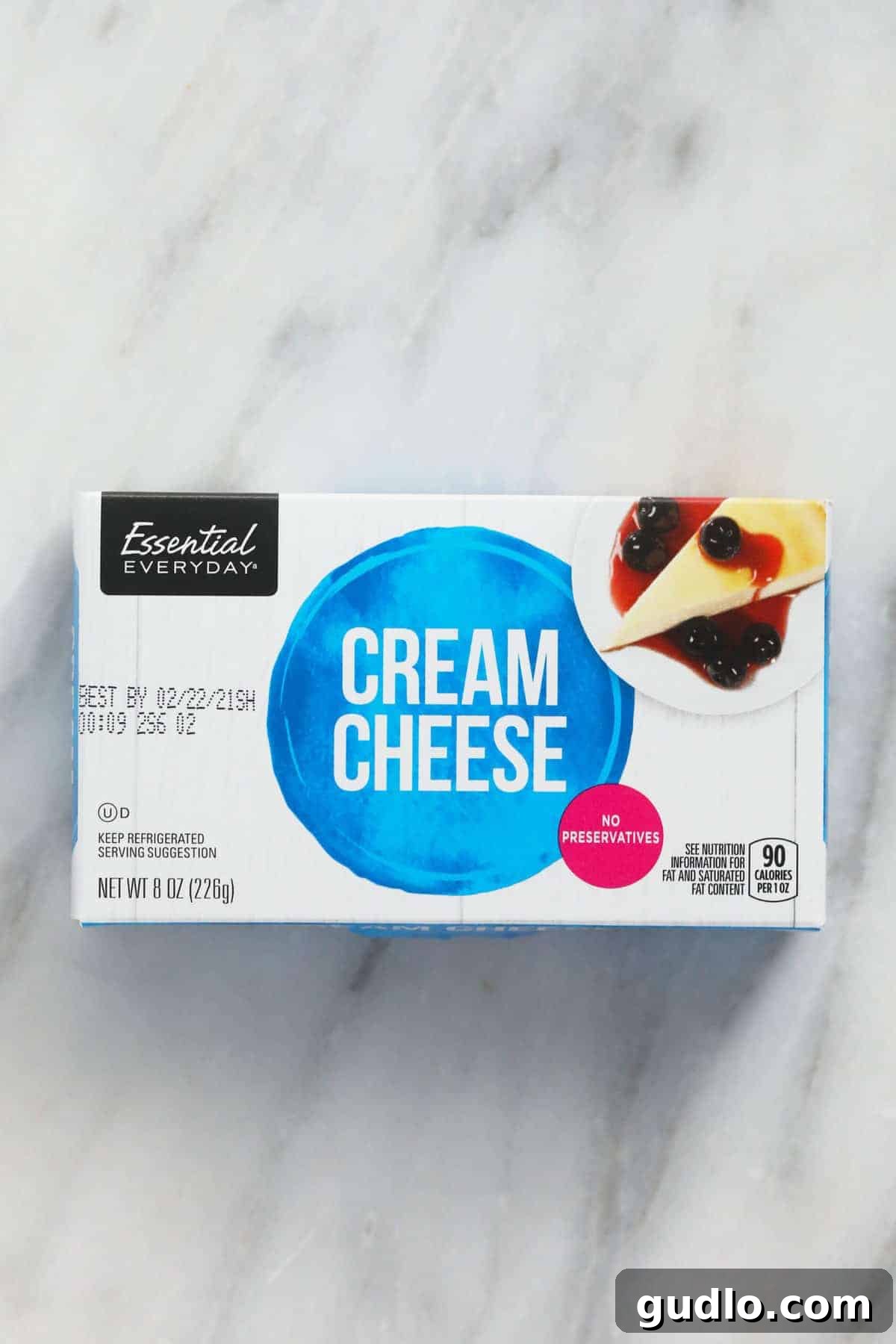 A block of cream cheese on a wooden surface, ready to be softened.