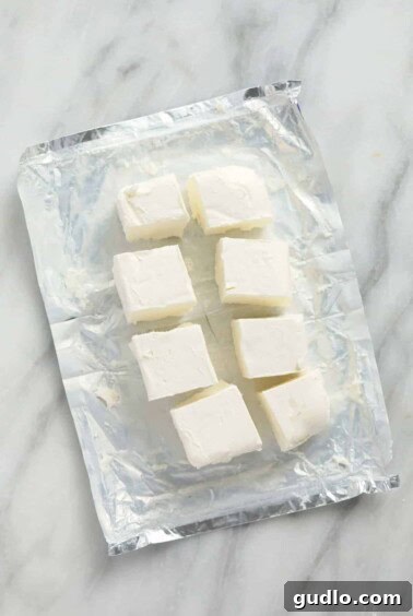 Cream cheese cubes on a countertop, aiding faster softening.