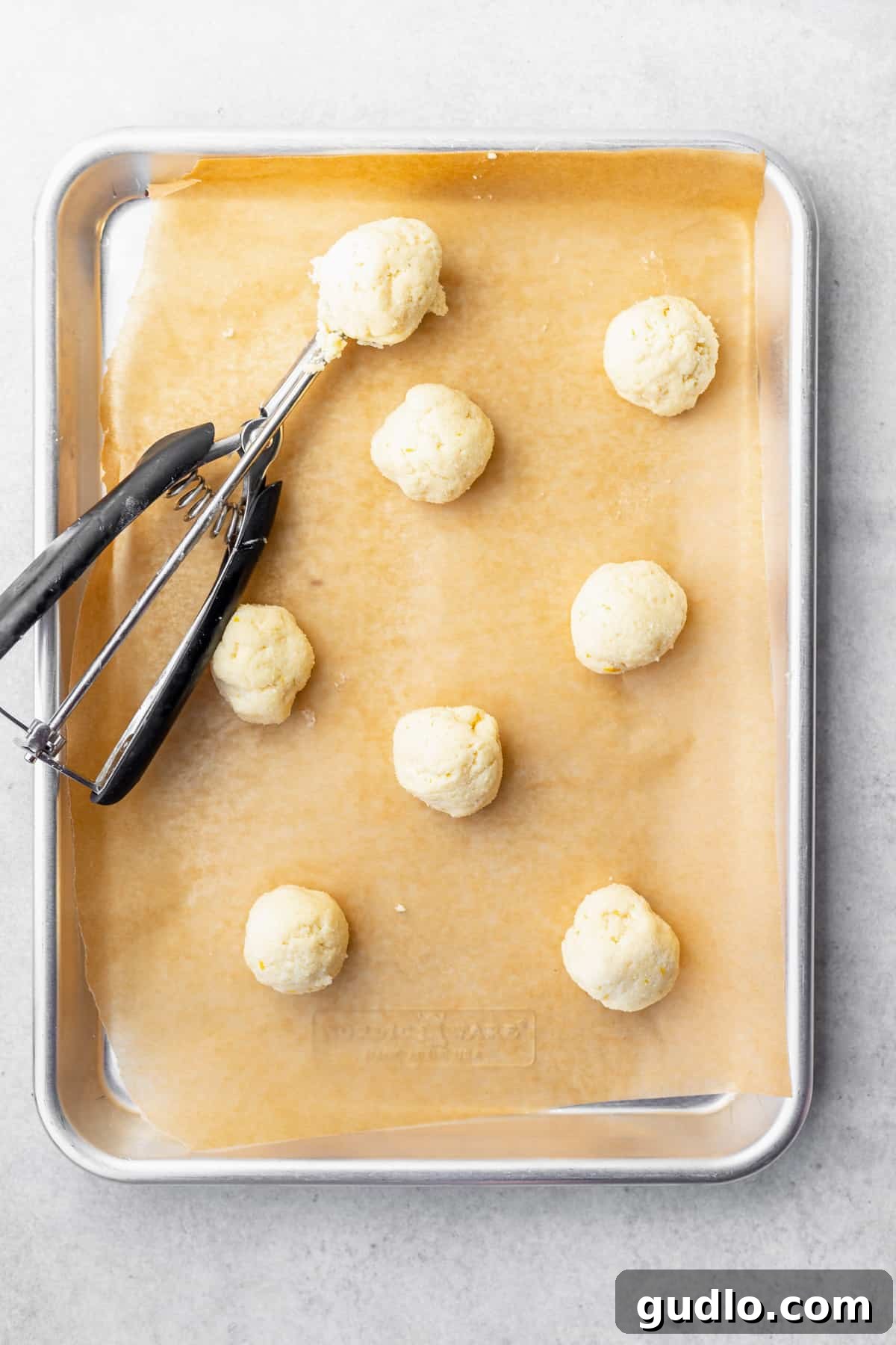 A baking sheet filled with freshly baked, unglazed ricotta cookies, showing their perfect round shape and golden bottoms.