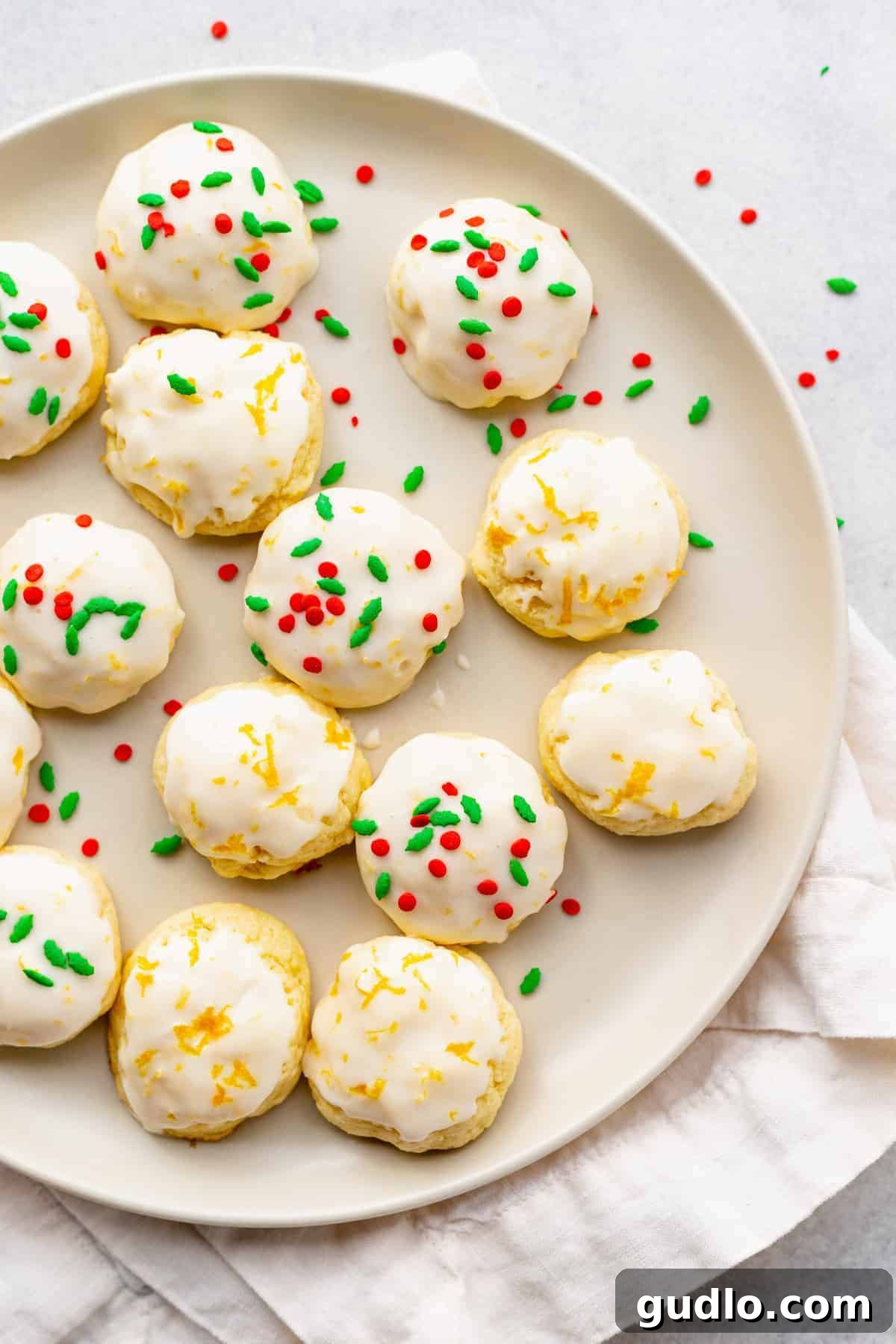 A plate of glazed ricotta cookies, adorned with colorful sprinkles, highlighting their festive and inviting appearance.