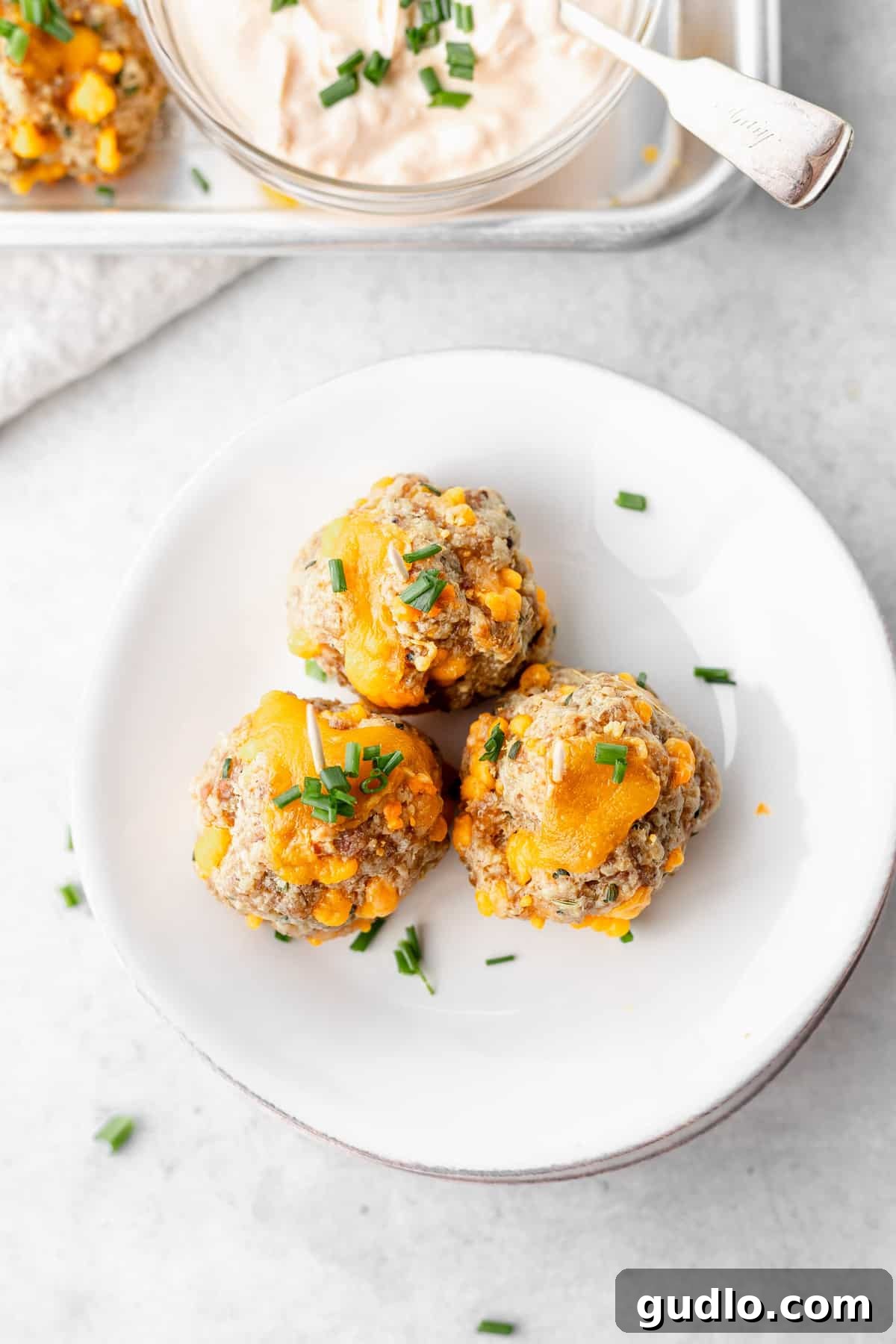 These Cream Cheese Sausage Balls make a fantastic appetizer for any occasion! Dip them in a perfectly zesty creamy garlic sauce, and enjoy! cream cheese sausage balls on a plate, ready to be served