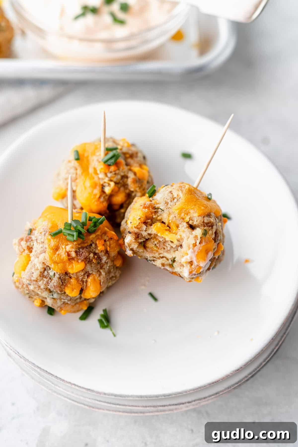 These Cream Cheese Sausage Balls make a fantastic appetizer for any occasion! Dip them in a perfectly zesty creamy garlic sauce, and enjoy! cream cheese sausage balls on a plate