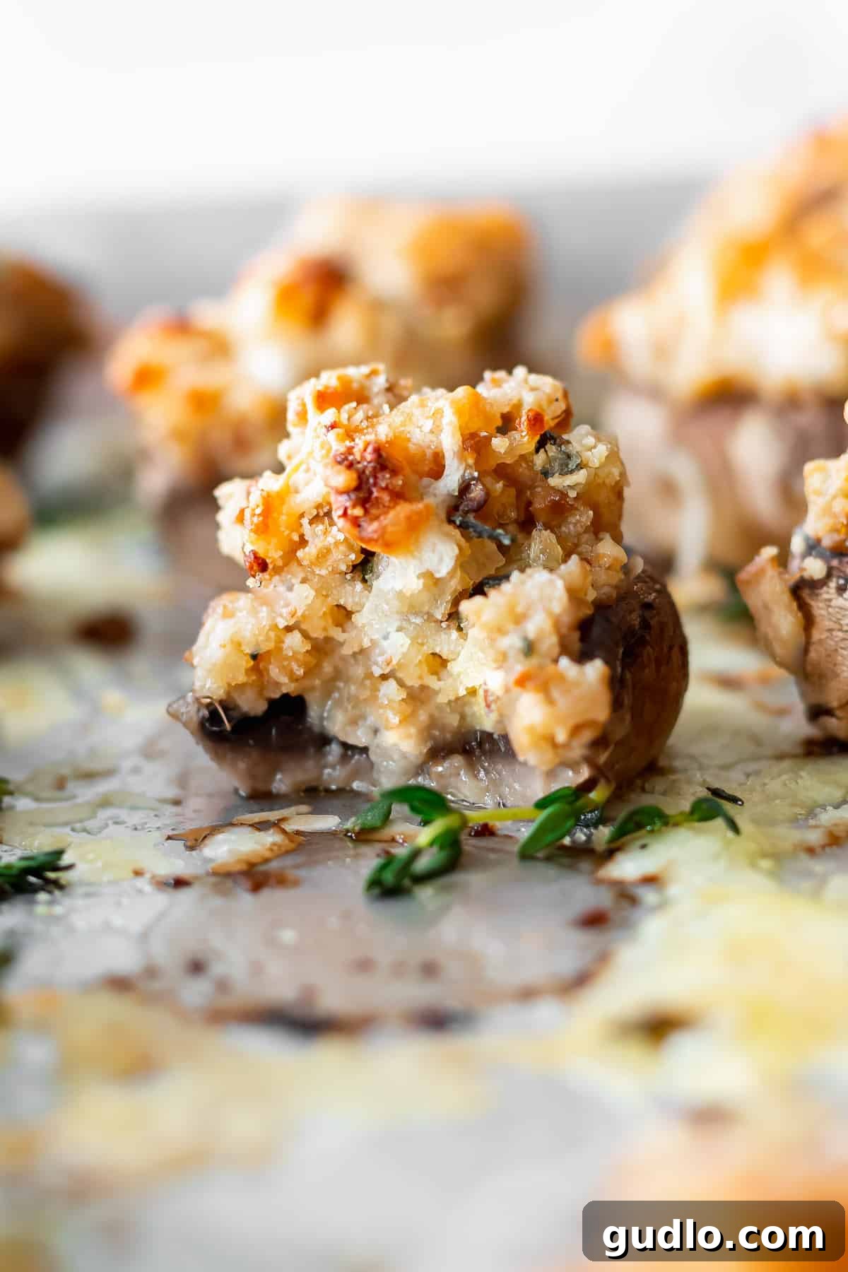A cream cheese stuffed mushroom with a bite taken out, revealing the creamy interior, artfully presented on a serving dish.