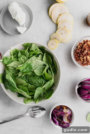 Salad ingredients, including spinach, red onion, and beets, ready for assembly in a mixing bowl.