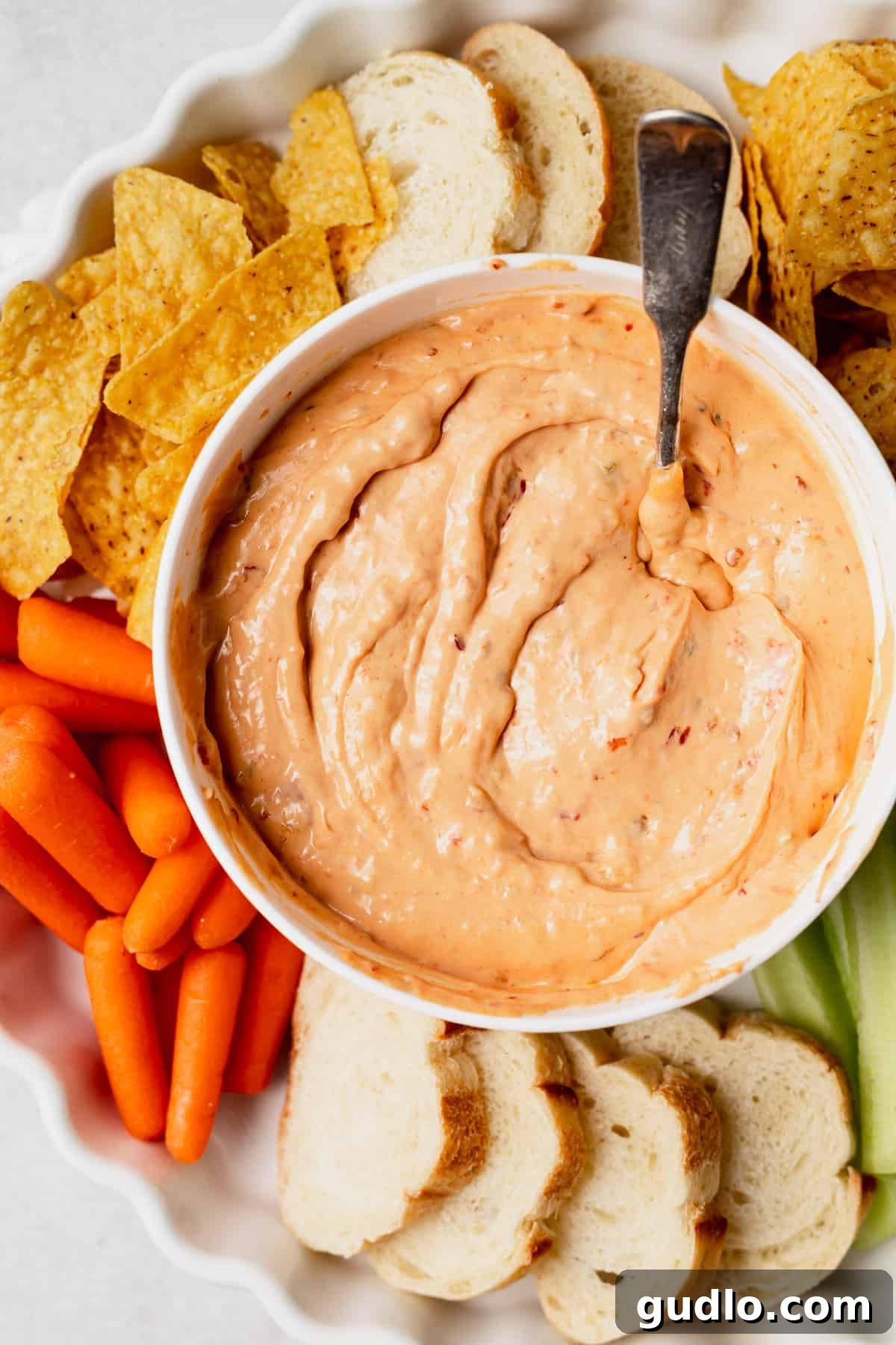 The Ultimate Slow Cooker Queso Dip A bowl of rich, creamy slow cooker queso dip, surrounded by crisp tortilla chips and fresh vegetable sticks ready for dipping.