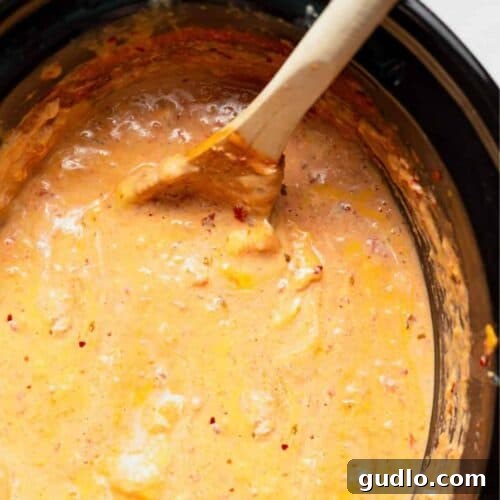 Ultimate Slow Cooker Queso 3 A crock pot filled with rich, golden queso dip, ready to be served.