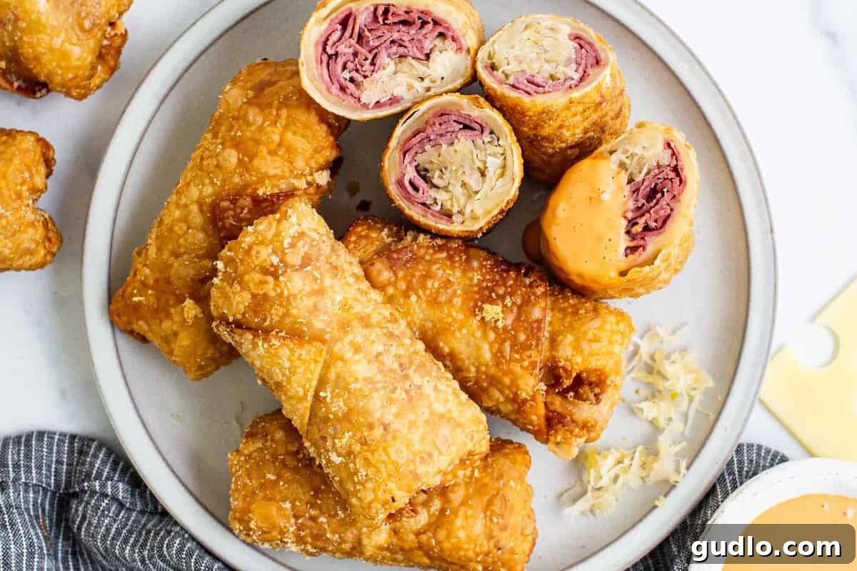 Crispy Reuben egg rolls served on a plate with a side of creamy dipping sauce.