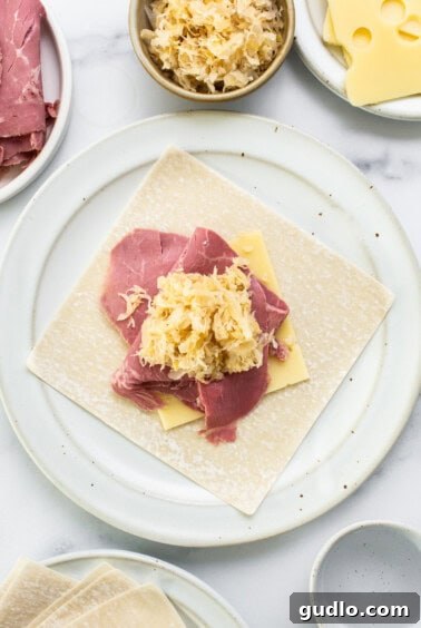 Assembling a Reuben egg roll with corned beef, Swiss cheese, and sauerkraut.
