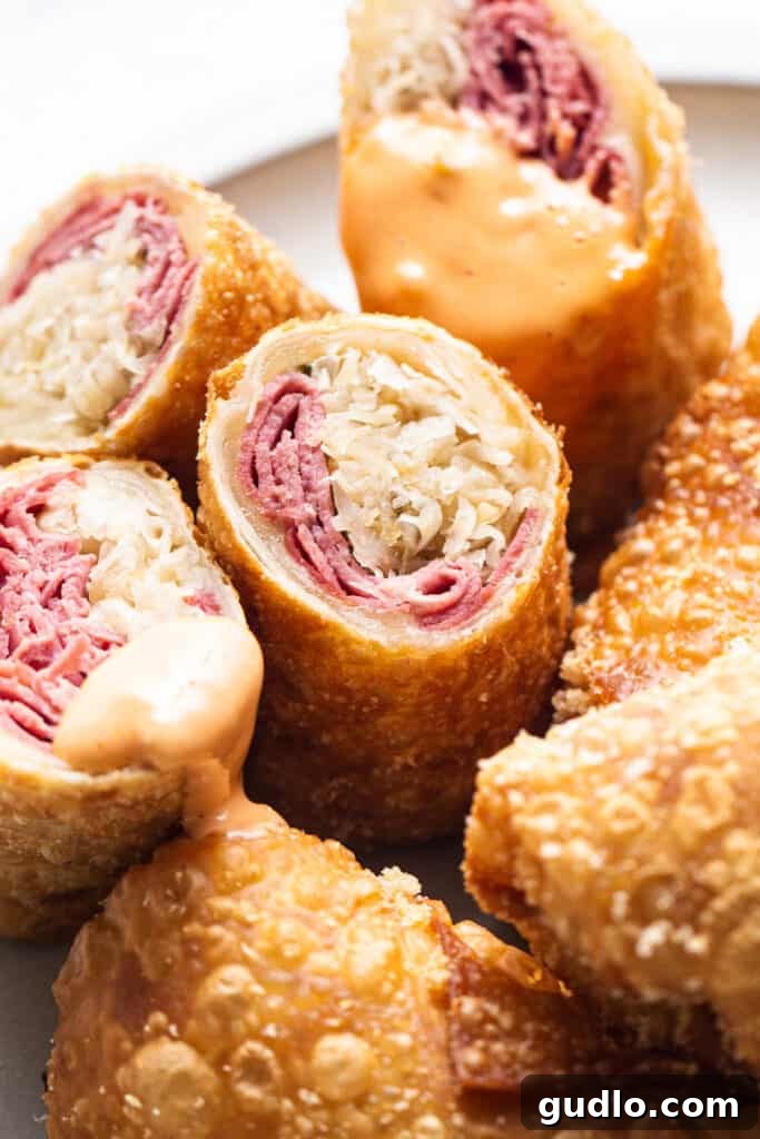 A close-up shot of perfectly fried Reuben egg rolls, cut in half to show the delicious filling.