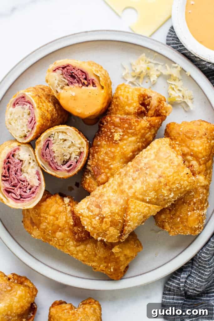 Crispy Reuben egg rolls stacked on a cooling rack, ready to be served.