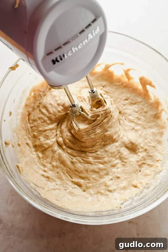 Morning Buzz Banana Cake 6 Using a hand mixer to combine the wet ingredients for a smooth banana coffee cake batter.