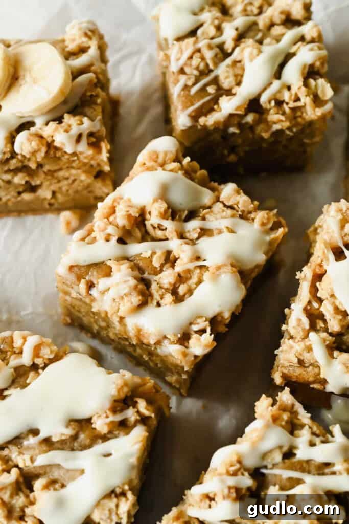 Morning Buzz Banana Cake 8 A close-up of sliced banana coffee cake squares drizzled with cream cheese icing on a serving plate.