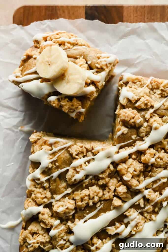 Morning Buzz Banana Cake 9 A single square of banana coffee cake with oat crumble and icing next to the full cake, ready to be served.