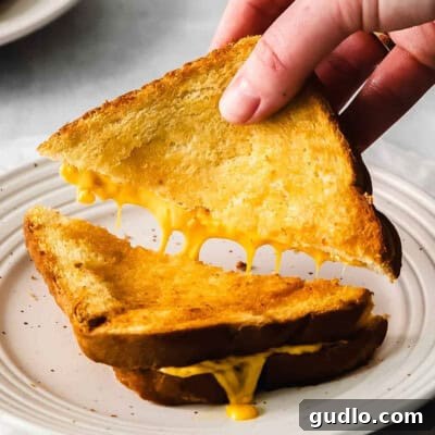 A person grabbing a piece of grilled cheese sandwich.