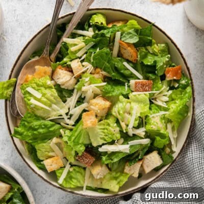 A bowl of caesar salad with croutons and parmesan cheese.