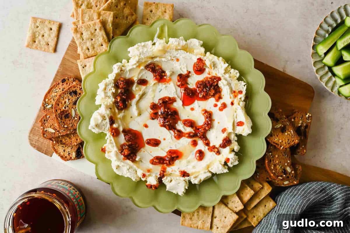 3-Ingredient Boursin Chili Crunch Dip Ready in 5 Minutes 2 Boursin chili crunch dip on a board with crackers, toast, cucumber slices, and a jar of chili crunch