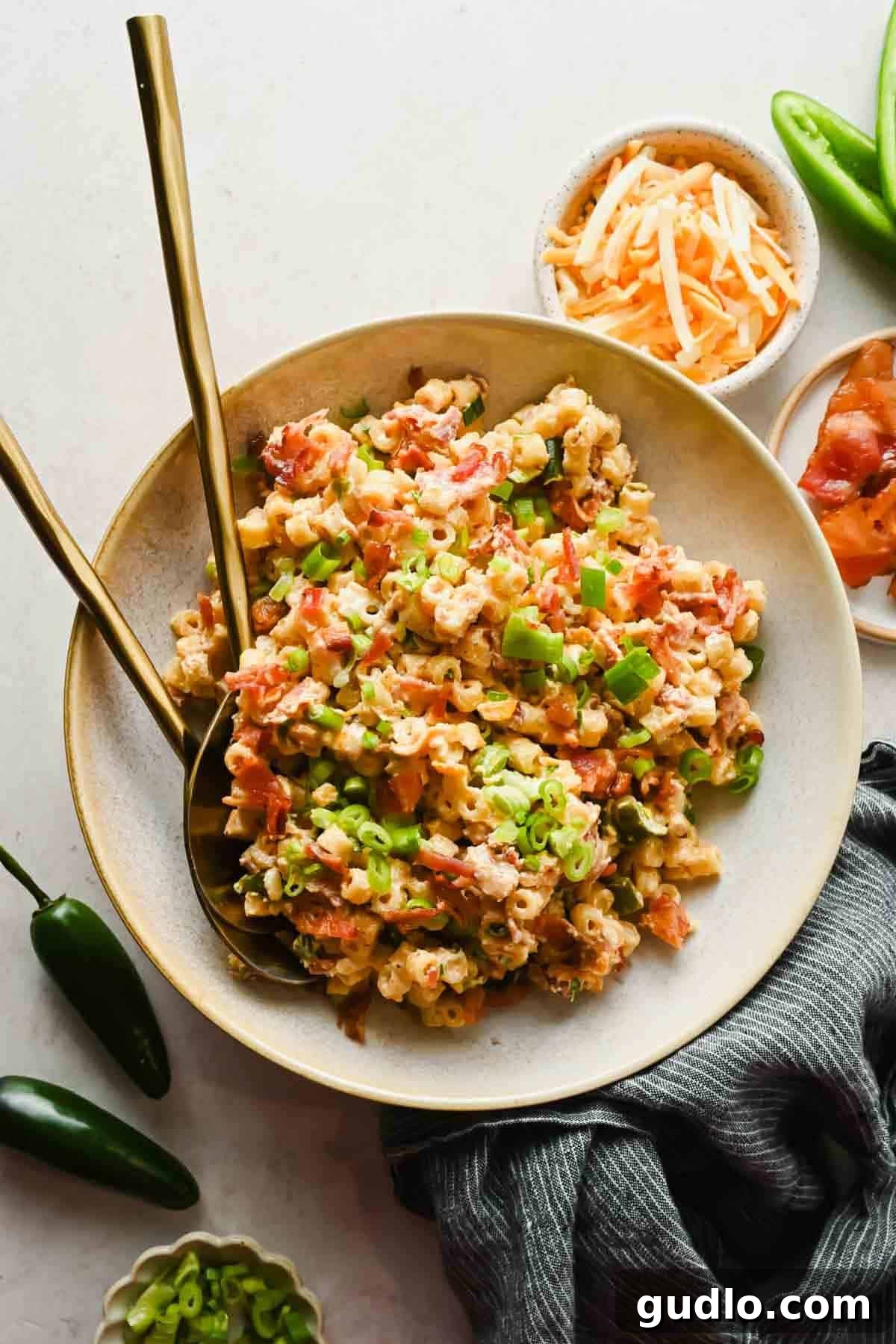 Jalapeño popper pasta salad in a large bowl with crispy bacon, green onions, and shredded cheese
