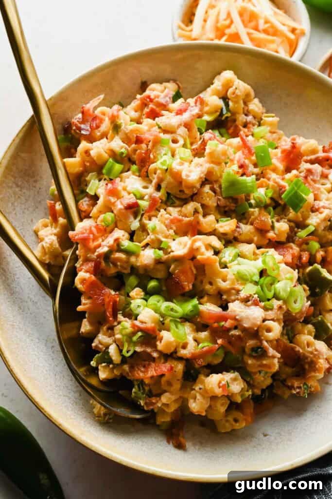 Jalapeño popper pasta salad with crispy bacon, green onions, and cheddar cheese served with gold utensils