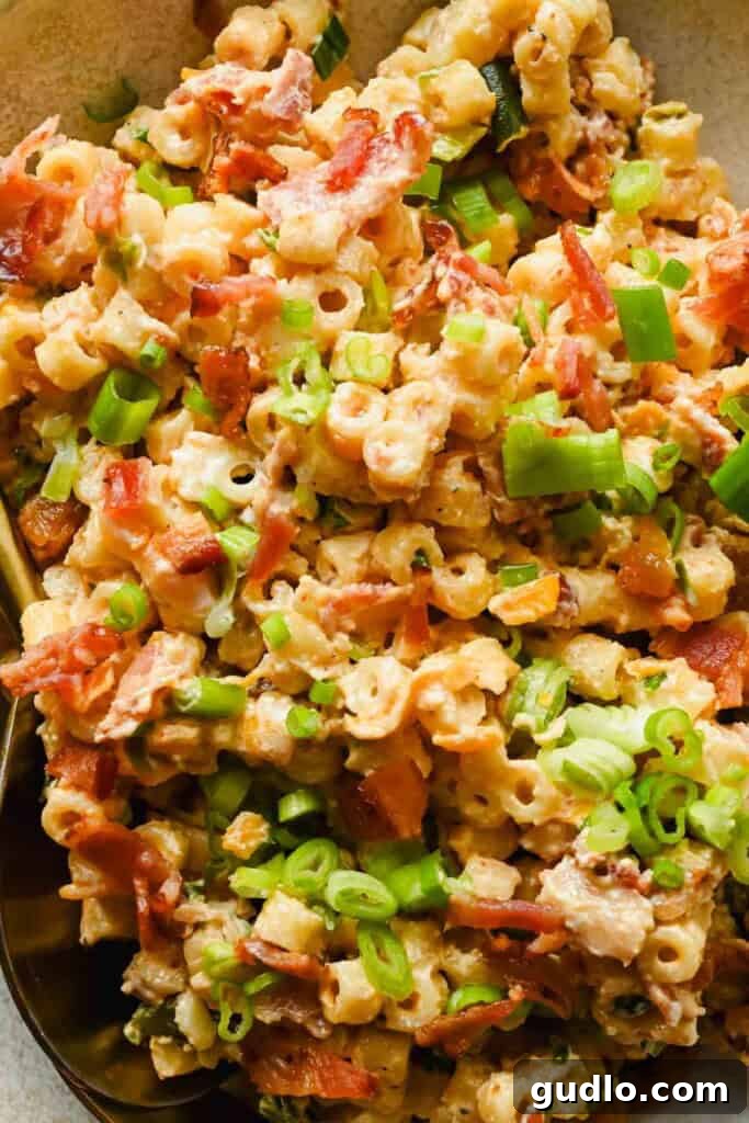 Close-up of creamy jalapeño popper pasta salad with chopped green onions and crispy bacon pieces