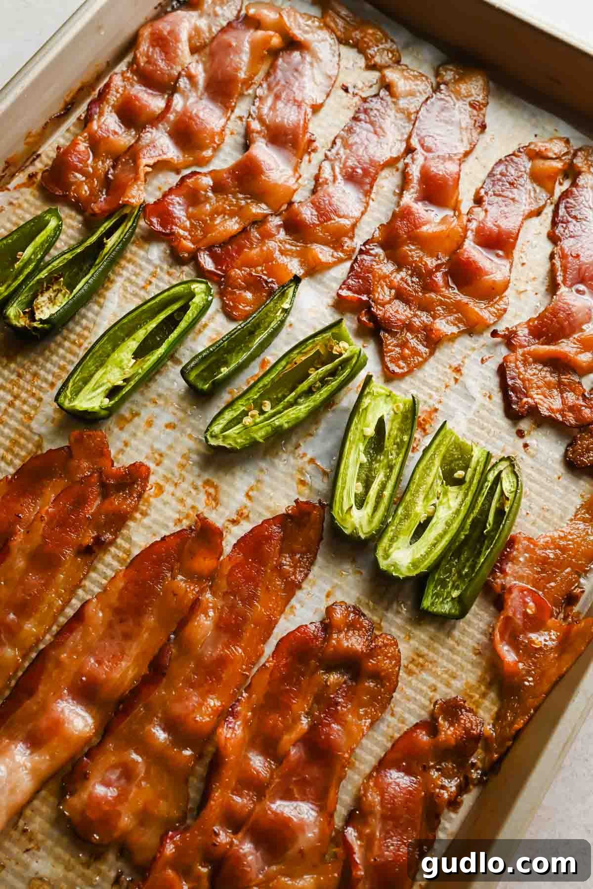 Crispy baked bacon and roasted jalapeños on a parchment-lined sheet pan