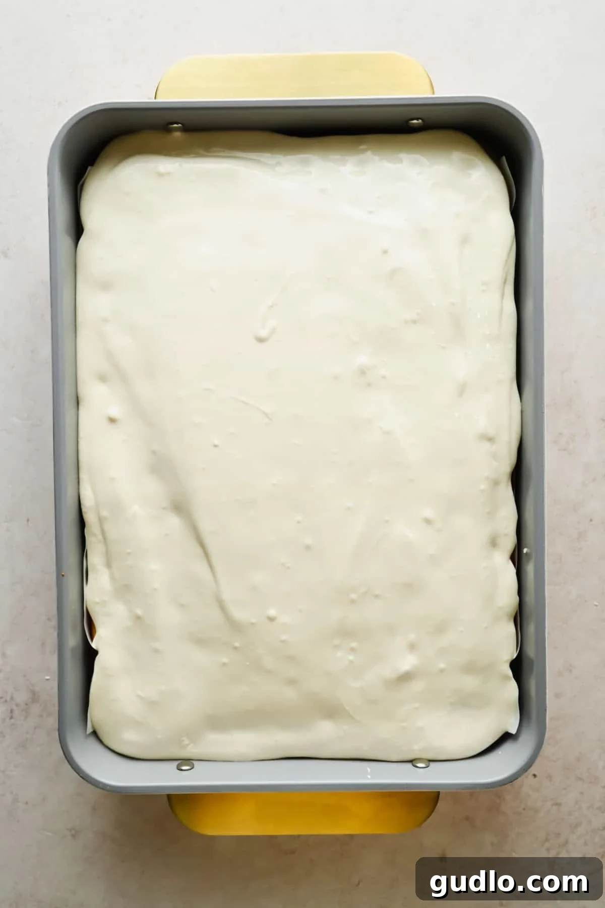 Moist Strawberry Poke Cake with Cream Cheese Frosting 7 Cream cheese frosting spread over a strawberry Jello poke cake in a baking pan