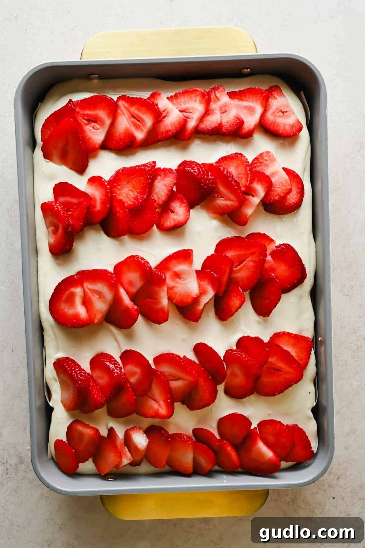 Moist Strawberry Poke Cake with Cream Cheese Frosting 8 Rows of sliced fresh strawberries arranged on top of frosted poke cake