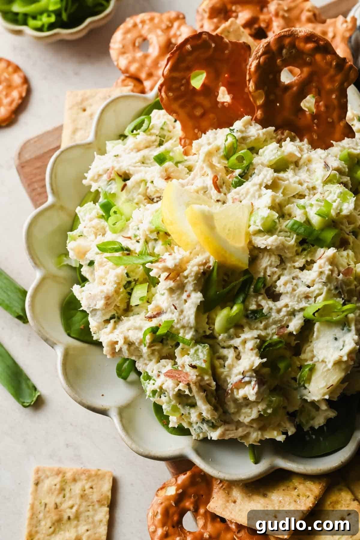 Spoonful of creamy Boursin chicken salad lifted from a serving bowl with celery and green onions.