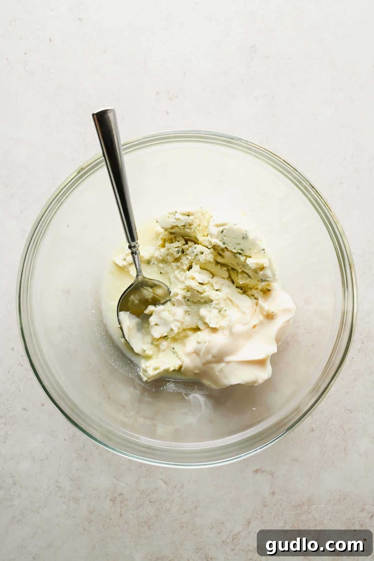 Boursin cheese, mayonnaise, and lemon juice in a clear mixing bowl before whisking.