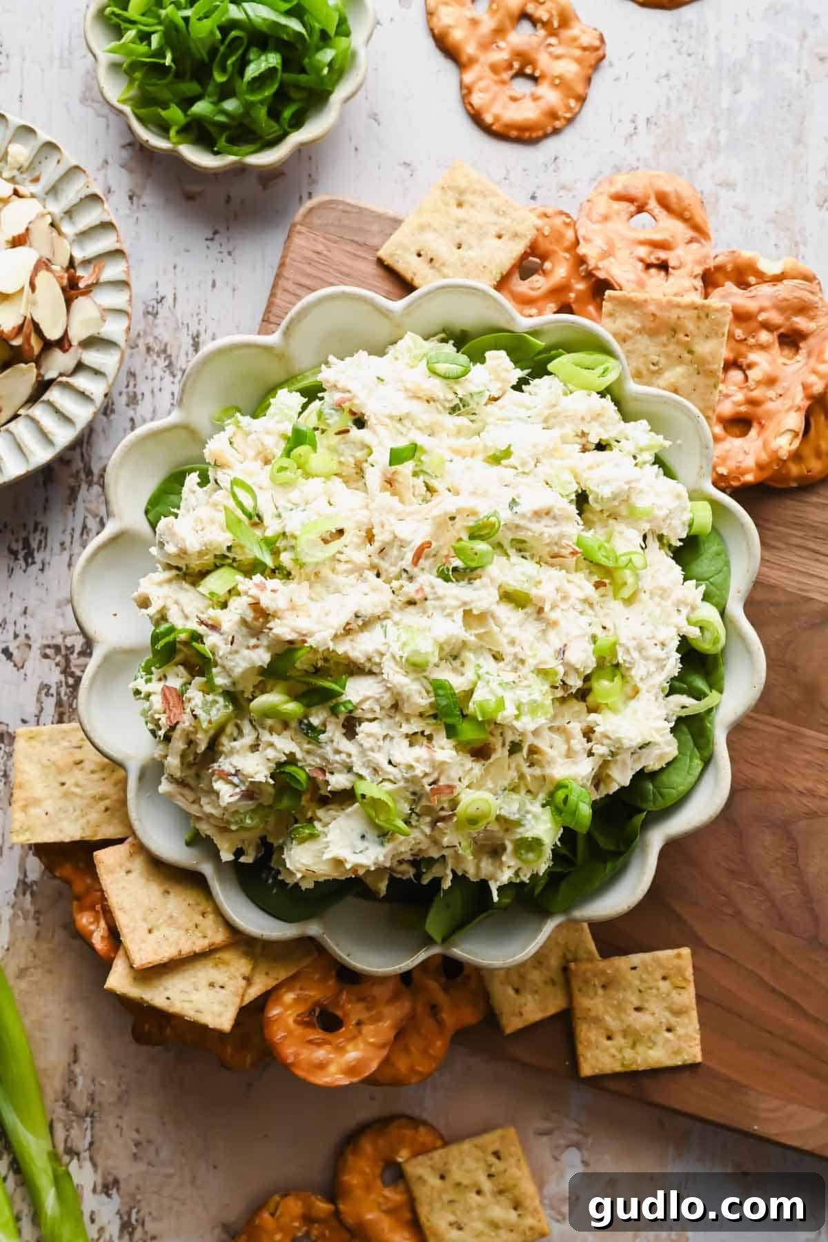 Creamy Boursin chicken salad spread served in a bowl with crackers and pretzels.
