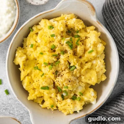 Scrambled eggs in a bowl with chives and sour cream.
