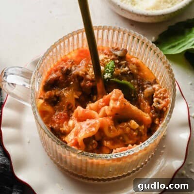 Microwave lasagna in a mug topped with melted cheese and fresh basil